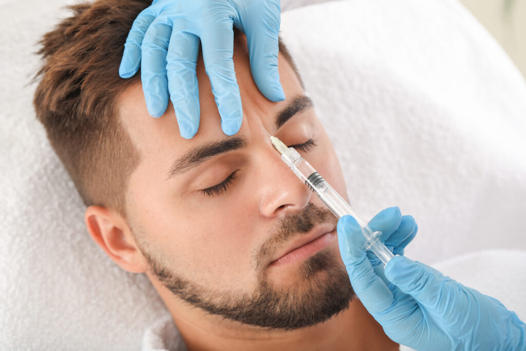 Mann erhält Botox zwischen Augenbrauen injeziert